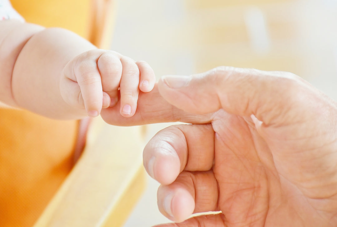 infant holding a grown-ups finger